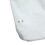 A close-up of Prada Dust bag showing two small brown stains on the surface highlighting it’s condition details 