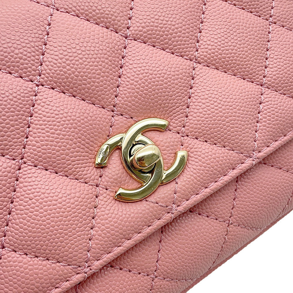 A close-up of a pink quilted leather handbag featuring a polished gold-tone interlocking CC turn-lock clasp, characteristic of Chanel.