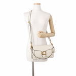 Close-up image of Coach Tabby 26 leather shoulder bag with gold-tone hardware and its Brand  'C' logo clasp, displayed on a mannequin torso, showing its crossbody look 
