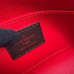 Close-up of a Louis Vuitton red leather interior with a dark brown stitched brand patch