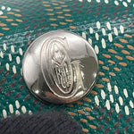 Macro view of the silver-tone metal snap button engraved with the signature Goyard G logo.