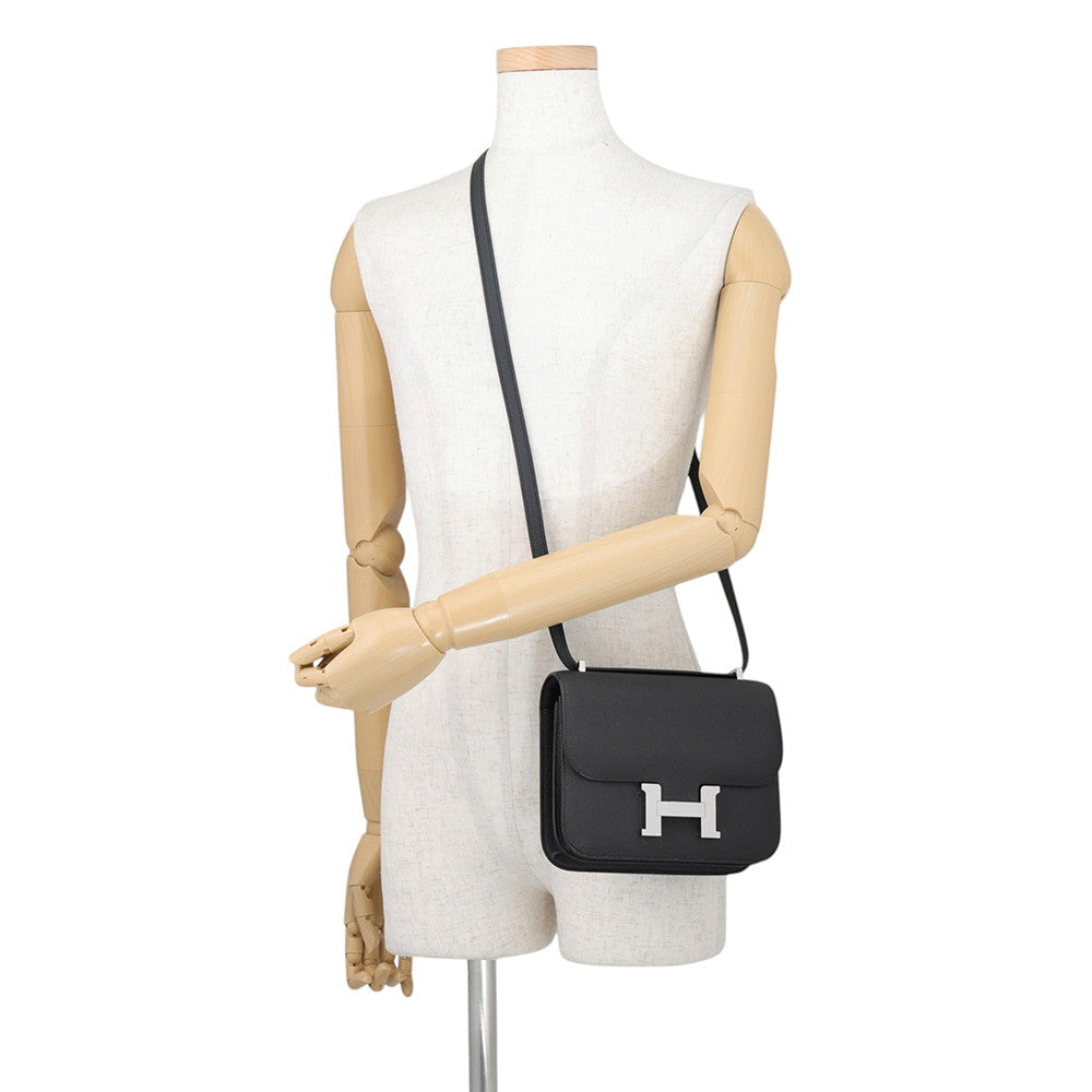 Mannequin wearing the Hermès Constance 18 in black Epsom leather extended as a crossbody bag.