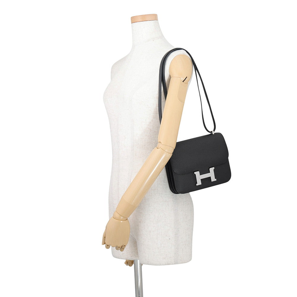 Mannequin styling the Hermès Constance 18 as a short shoulder bag with doubled leather strap.