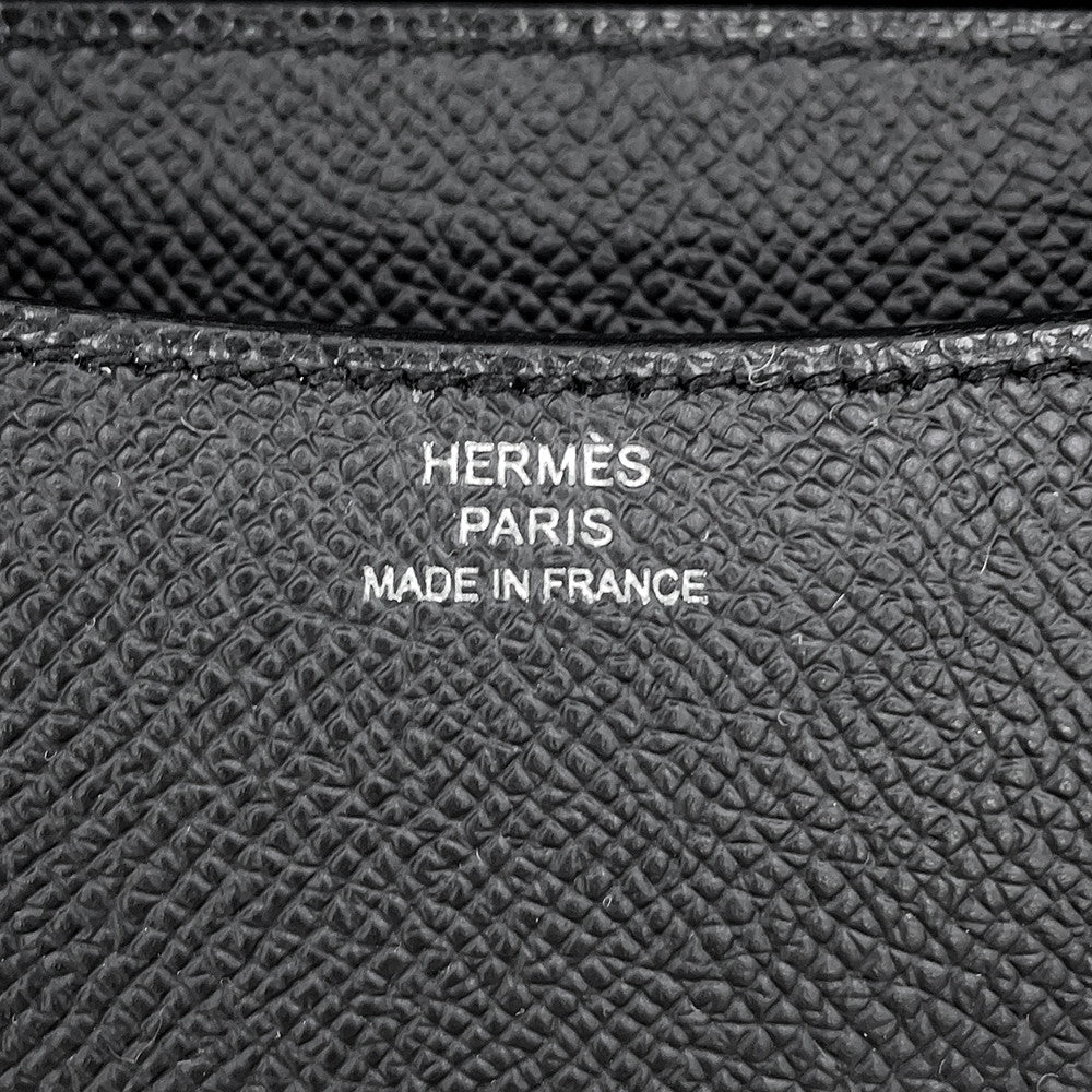 Macro detail shot of the silver foil Hermès Paris Made in France logo heat stamp on black leather.