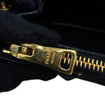 Close-up of a black leather zipper with a gold-tone metal pull engraved with 'PRADA MILANO”, detailing minor scratches on zipper surface 