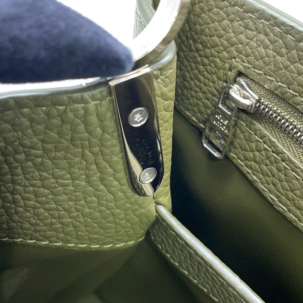 Close-up of silver-tone engraved zip pull and side hardware on Capucines BB