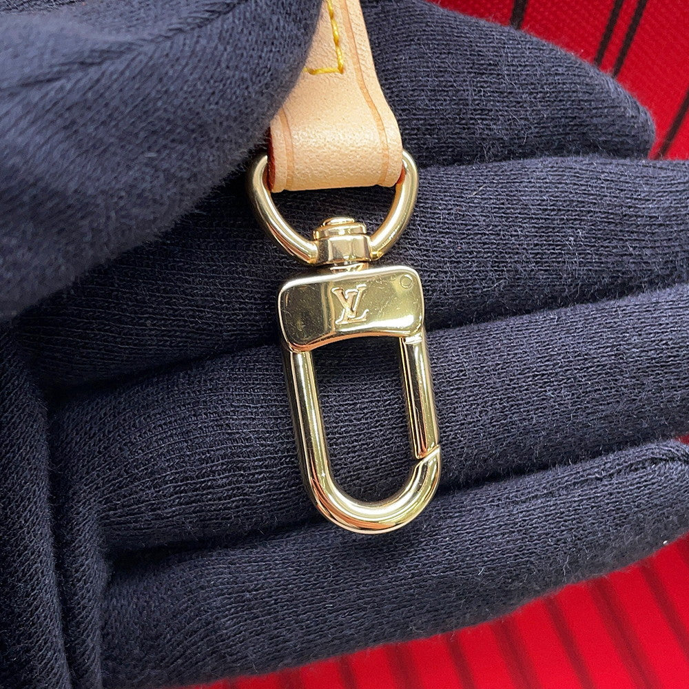 Detailed view of gold-tone LV engraved interior carabiner clasp on Louis Vuitton Neverfull MM