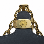 Close-up detail of the antique-finish brass strap hardware and engraved Coach logo clasp.