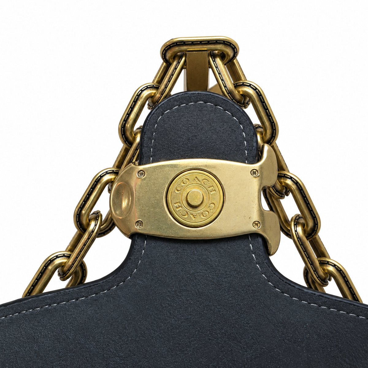 Close-up detail of the antique-finish brass strap hardware and engraved Coach logo clasp.